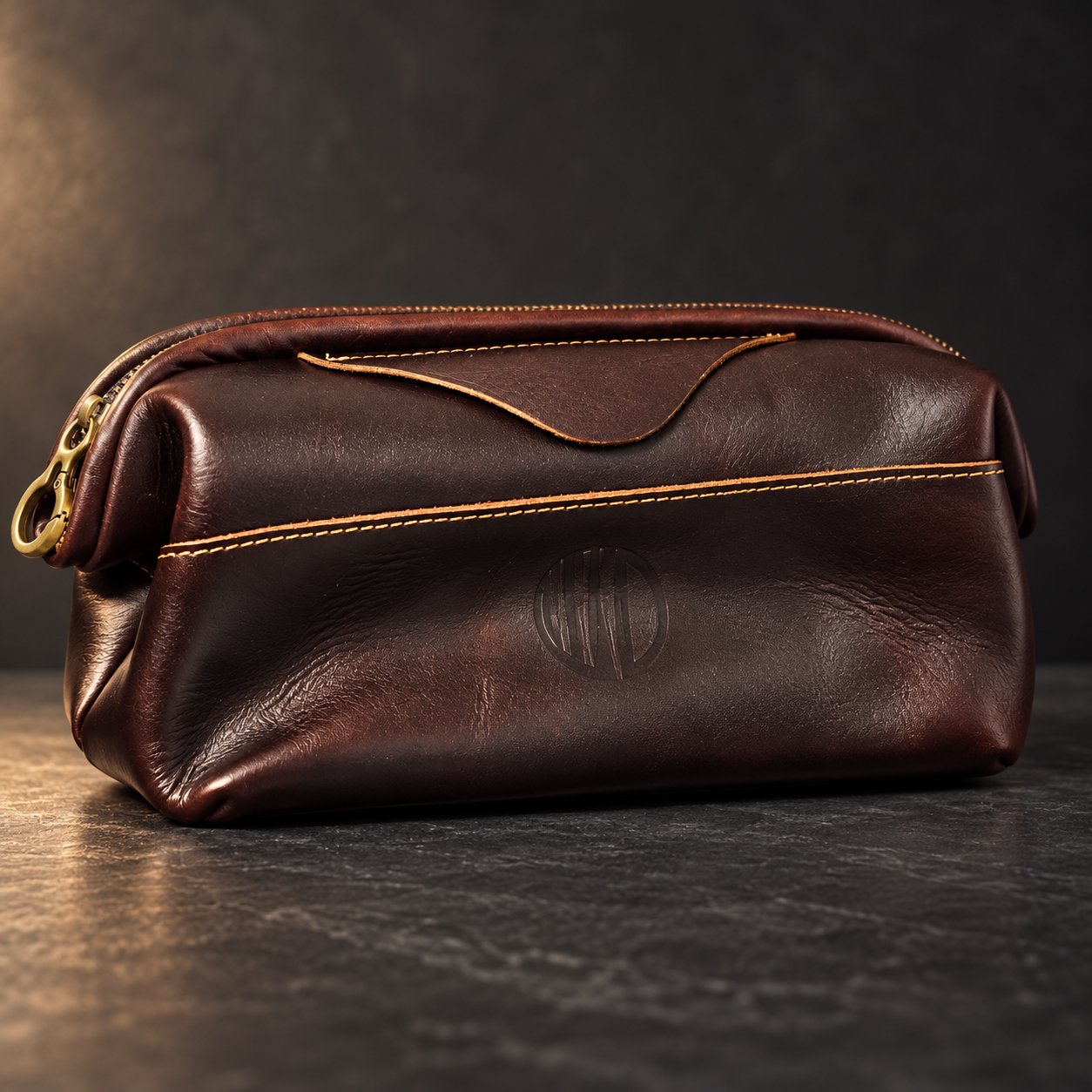 Front view of the Vintage Coffee Leather Pouch on dark slate with its engraved logo